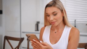 Blond happy beautiful female working from home sits at table does video call to contact colleagues
