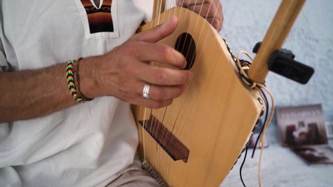 Close-up male greek hands playing lyre string instrument