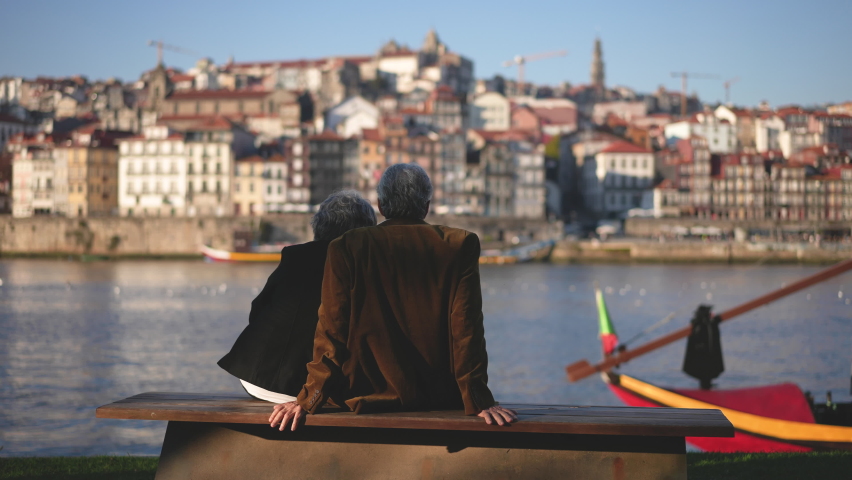 European Portuguese elderly family couple of tourists sitting together at Duero river quay in Porto. Tourism traveling in Portugal. Display of love, affection by elderly people. Person touching moment Royalty-Free Stock Footage #1083993403