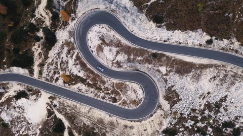 Aerial drone view on winding mountains road leading to Three peaks of Lavaredo in Tre Cime di Lavaredo National Park in Dolomite Alps. Foggy larches forest around. Autumn in Dolomites, Italy