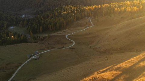 Drone flight over Fuchiade valley in Italian Dolomites countryside in autumn time. Wooden huts, orange larches forest and mountains peaks on background. Dolomite Alps, Italy. UHD 4k video