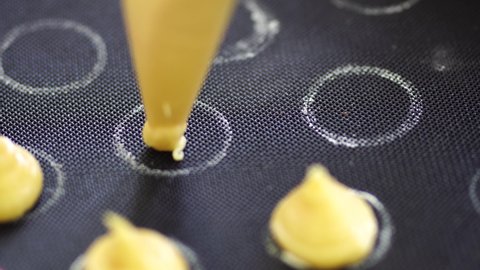 Pastry chef squeezes choux au craquelin from a pastry bag on a silicone mat