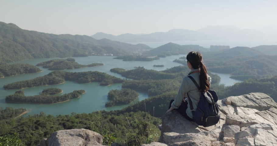 Woman sit on the top of mountain and look at the scenery view