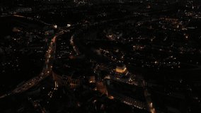 Aerial drone night video of small illuminated Tiber Island with a number of historical monuments next to iconic Marcello Theatre and Tempio Maggiore, Rome, Italy