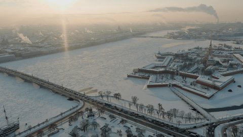 Drone footage of winter view of St. Petersburg at sunset, frozen Neva river, steam over city, Peter and Paul fortress, car traffic on Trinity bridge, rostral columns, Palace drawbridge, panoramic view