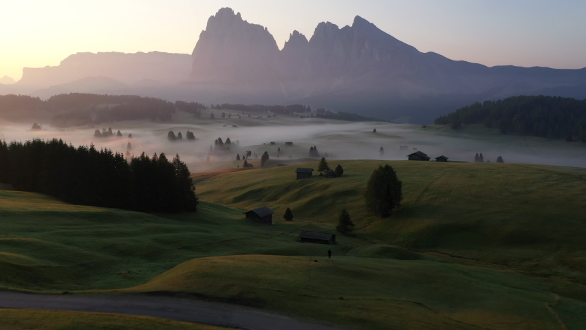 Drone aerial view of Alpi di Siusi, Seiser Alm. Dolomiti mountains, South Tirol, Dolomiten mountains view, Italian Alps. Clouds moving fast. Sunrise Royalty-Free Stock Footage #1084014694