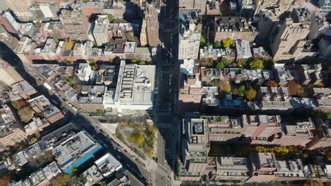 High angle view of wide street leading between tall buildings. Houses are arranged into blocks in regular grid. Manhattan, New York City, USA