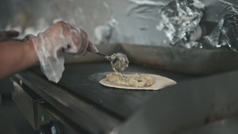 Close up of unrecognizable hands filling tacos with beef mixture on pita oven in kitchen