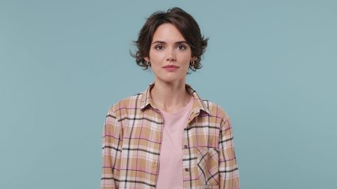 Excited jubilant overjoyed young brunette woman 20s years old wears plaid shirt doing winner gesture celebrate clenching fists say yes isolated on pastel plain light blue background studio portrait