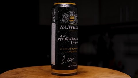 Black aluminum can of unfiltered Baltika beer with condensation droplets. Russian beer on a wooden background. The camera flies around. Parallax effect. Russia, Krasnodar, December 10, 2021