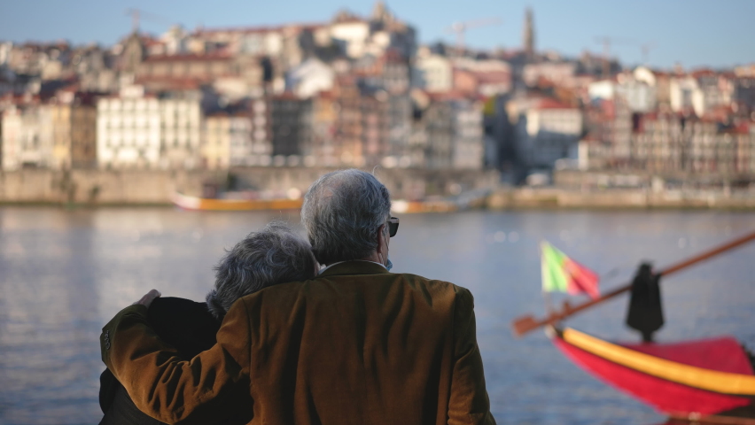 European Portuguese elderly family couple of tourists sitting together at Duero river quay in Porto. Tourism traveling in Portugal. Display of love, affection by elderly people. Person touching moment Royalty-Free Stock Footage #1084038928