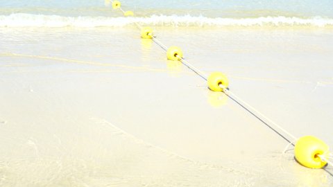 Buoyant swim lane section divider safety line. Yellow marker swim area buoys on sea. Yellow floating buoy over ocean. Video 4k footage 2022.