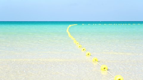 Buoyant swim lane section divider safety line. Yellow marker swim area buoys on sea. Yellow floating buoy over ocean. Video 4k footage 2022.