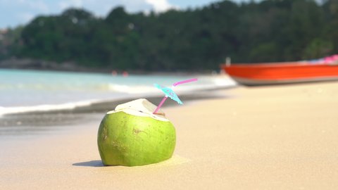 Coconut drink on sandy beach during sunset. Coconut juice with straw tropical island. Video close up. Video 4k footage 2022.