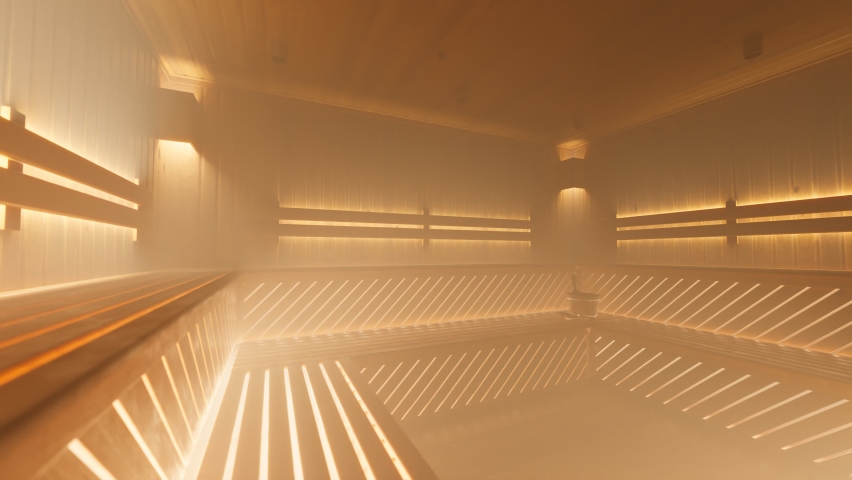 Dense steam in a warm, brightly illuminated wooden sauna room. A modern healthy way of life. Empty space prepared for a few people to rest. Beautiful wooden blanks pattern. Royalty-Free Stock Footage #1084041613