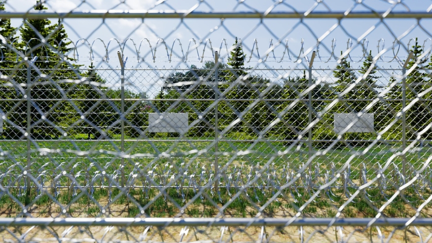 Boundary fence between two countries. Illegal refugees migrations preservation. Borderland territory. A permanent barricade made of metal barbed wires with sharpened spikes on the top. Forest scenery