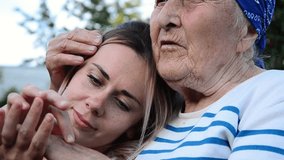Two generations of women. Hugs of grandmother and granddaughter. Parents and children concept. The granddaughter gives flowers to her grandmother. Mothers Day. Happy grandmother with her granddaughter - Powered by Shutterstock - Get 15% off with code: PIKWIZARD15