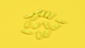 Yellow capsules on yellow background. Side view. Loop motion. Rotation 360. 4K UHD video footage 3840X2160.