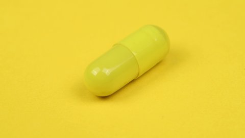 Yellow capsule on white background. Side view. Loop motion. Rotation 360. 4K UHD video footage 3840X2160.