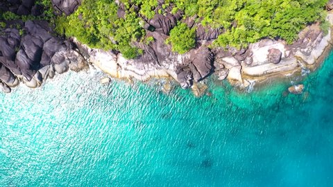 Drohnenclip an einem wunderschönen Strand auf Mahe mit türkisblauem Wasser, Felsen und Palmen auf den Seychellen