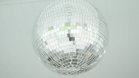 Disco ball hangs from roof shining in natural lighting
