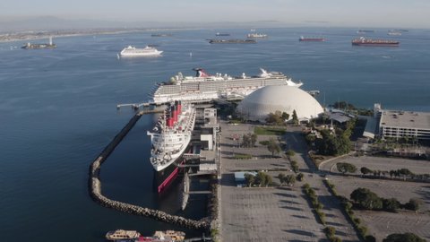 Long Beach , CA , United States - 12 08 2021: Aerial over the Queen Mary ocean liner with long line of container ships in the background.