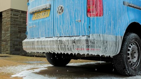 Devon , United Kingdom (UK) - 08 17 2021: Blue SUV Car Covered With White Foamy Soap Suds At Daytime
