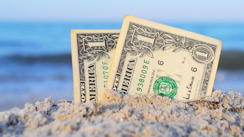 Two one dollar bills half buried in sand on sandy seashore close-up. Two paper dollar bills half in sand on sea beach on sunny day. Concept money, finance, investment, wealth, poverty, financing, cash