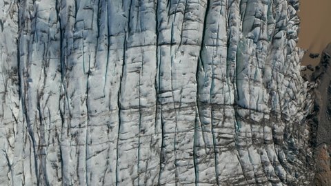 Top down view of cracked ice of Breidamerkurjokull glacier in Vatnajokull national park with brown mud ice. Overhead view of icy formation of frozen glacial permafrost in arctic Iceland