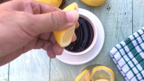 Someone is squeezing a lemon into a black coffee in a white cup. healthy drink lemon coffee.