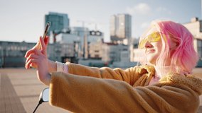 Close up portrait of young cheerful woman with pink hair wearing sunglasses making selfie, enjoying sunlight in city, tracking shot, slow motion - Powered by Shutterstock - Get 15% off with code: PIKWIZARD15