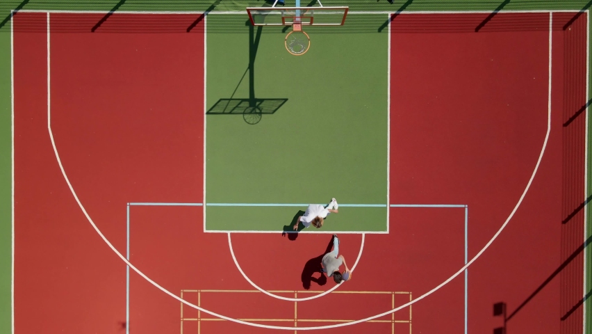 Aerial view of two young male friends playing basketball on court outdoors. Royalty-Free Stock Footage #1084075651