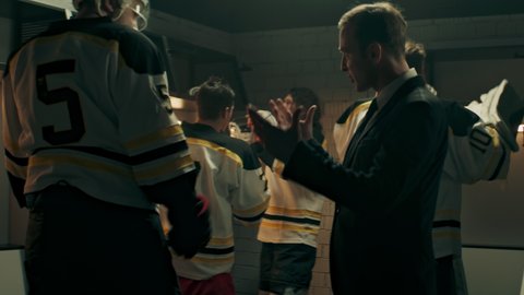 Happy positive coach greeting ice hockey team players on the locker room during the intermission. Motivation speech. Shoot with 2x anamorphic lens
