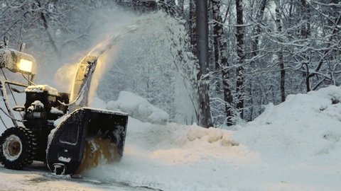 Snow-covered man cleans the road in winter with blower, snow removal equipment