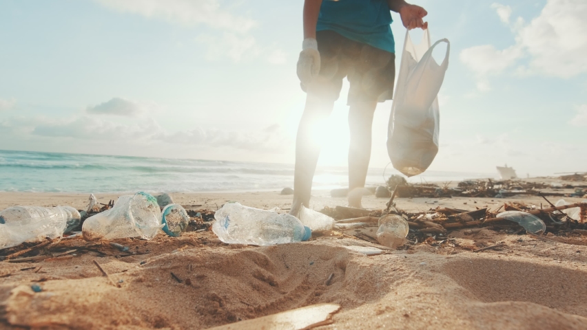 Young Caucasian woman environmental activist volunteers cleaning beach from non-degradable plastic waste saving world's oceans from pollution walks on sea sand at low tide. Caring for nature concept Royalty-Free Stock Footage #1084095199