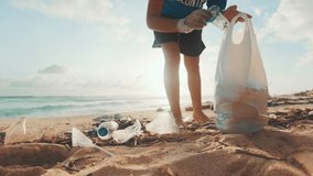 Young Caucasian woman environmental activist volunteers cleaning beach from non-degradable plastic waste saving world's oceans from pollution walks on sea sand at low tide. Caring for nature concept - Powered by Shutterstock - Get 15% off with code: PIKWIZARD15