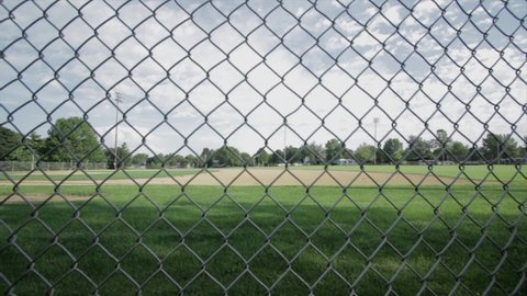 Empty and lonely baseball field seen through a chain link fence