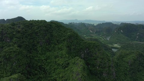 aerial drone shot appearing behind the mountain in Ninh Binh National park, Vietnam. Unesco world heritage, ecological paradise, skull island.