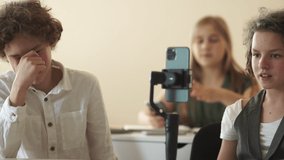 Funny schoolgirl blogger. Cute curly-haired girl schoolgirl records a video for social networks using a steadicam and a smartphone