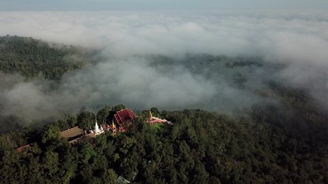Aerial view of Wat Phra That Doi Phra Chan temple with fog located on the serene top hill in Mae Tha district, Lampang province of Thailand.