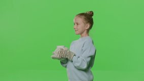 Pretty smiling girl drinking tea isolated on green screen background. Young white kid with hot drink smiling on Chroma key. 4k raw video footage slow motion