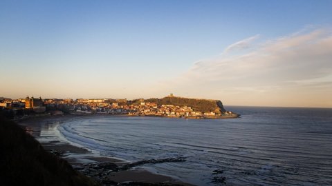 time lapse looking over Scarborough Castle Headland and harbour as the setting sun casts the last light of day