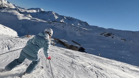Slow motion: Young woman skiing on a winter holiday, camera follows skier down the slope 