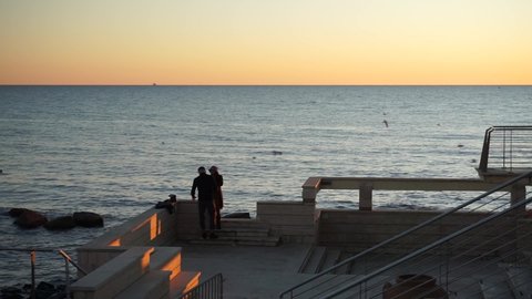 Ostia, Rome, Italy - December 19, 2021, people are relaxing and a couple is watching the sunset from the historic La Vecchia Pineta bathhouse.