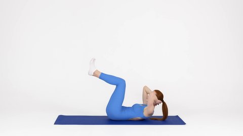 Fitness Workout. Sporty Young Woman Making Elevated Crunch Exercise In Studio, Fit Female In Blue Sportswear Training Abs Core Muscles While Lying On Yoga Mat Over White Background, Side View