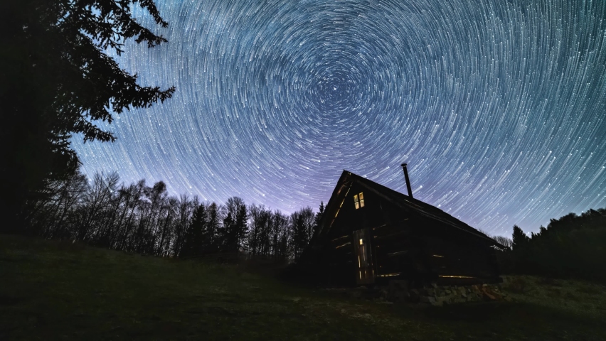 Startrail, Milky way galaxy star trails rotates over old wooden hut in night sky forest nature Astronomy Time lapse 4K