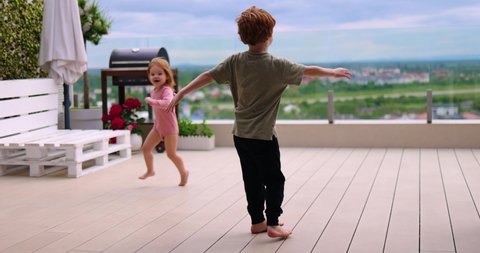 playful kids having fun on rooftop patio at summer evening at home
