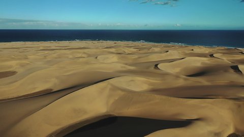 Impressive natural sand dunes in Gran Canaria, Canary islands, Spain. Aerial view of a tiny desert and the beach by the Atlantic ocean on a sunny day in Maspalomas.