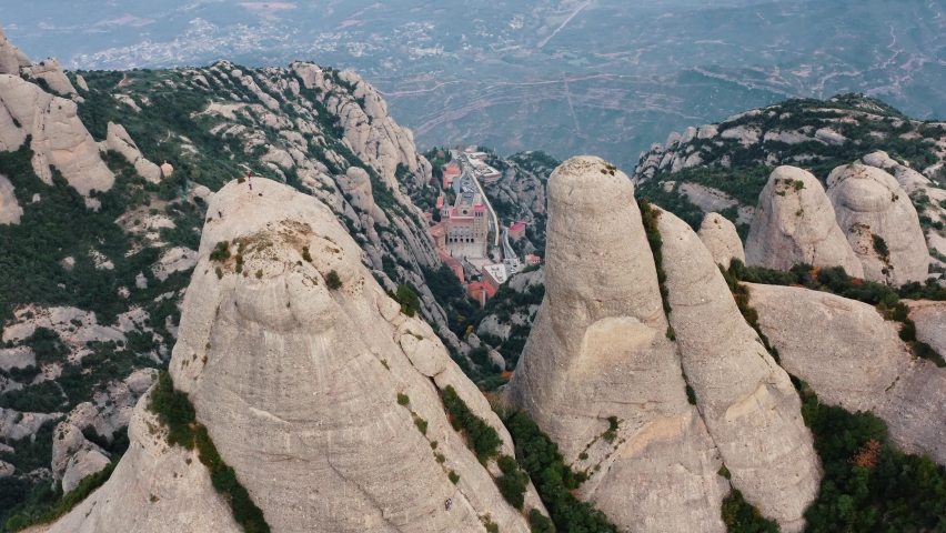 Aerial drone shot of multi peaked mountain Montserrat with Santa Maria de Montserrat monastery. Site of Benedictine abbey in Barcelona, Catalonia, Spain. Tourism, travelling. Slow motion