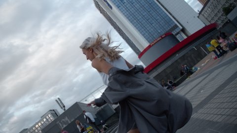 Beautiful woman with blonde hair walking stairs energetically in urban backgorund. Side view active female person going upstairs while wearing casual wear in city landscape. Walking city concept.